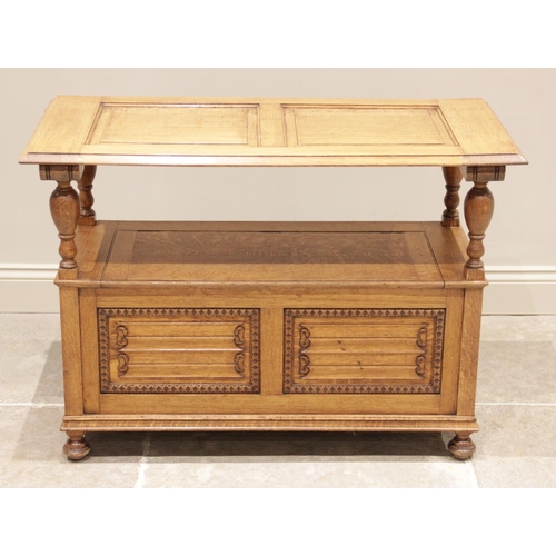 728 - An early 20th century golden oak monks bench, the 'up and over' back panel carved with linen fold de... 