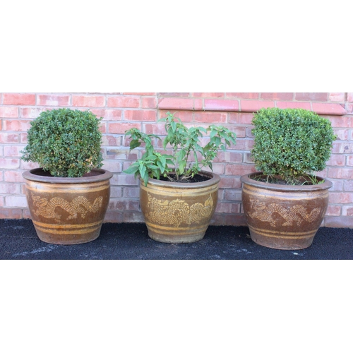 751 - A trio of modern glazed stoneware garden planters, of tapering form with applied painted dragon deta... 