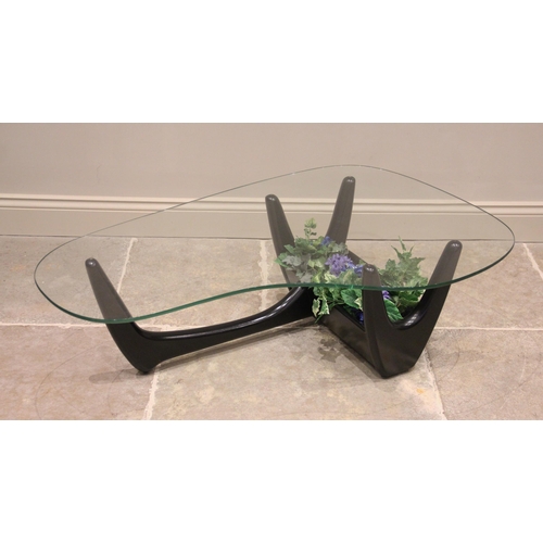 732 - A mid century glass top coffee table in the manner of Adrian Pearsall, the shaped glass top on an eb... 