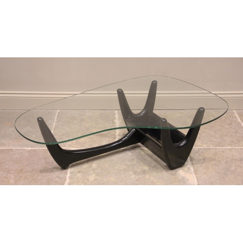 732 - A mid century glass top coffee table in the manner of Adrian Pearsall, the shaped glass top on an eb... 