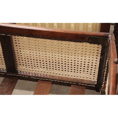 709 - A Victorian mahogany and rattan cradle, the ogee shaped canopy with turned finials above rattan side... 