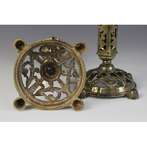 610 - A pair of Victorian brass candlesticks, each cast with arabesques and masks above a domed and pierce... 