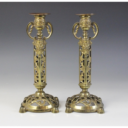 610 - A pair of Victorian brass candlesticks, each cast with arabesques and masks above a domed and pierce... 