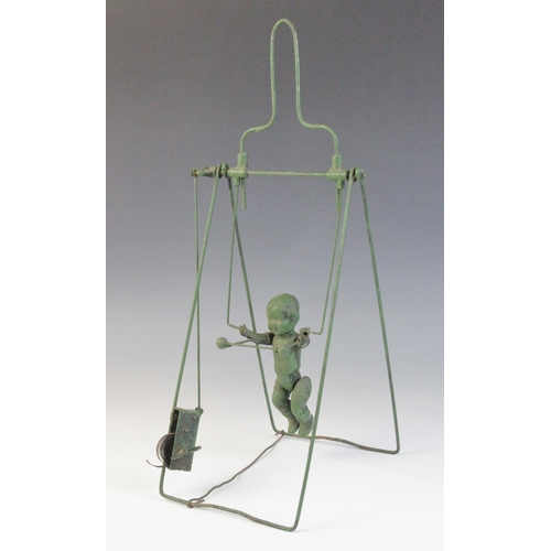 673 - A celluloid and wire spring driven trapeze toy, 33.5cm high (at fault)