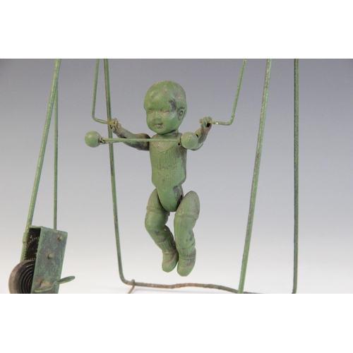 673 - A celluloid and wire spring driven trapeze toy, 33.5cm high (at fault)