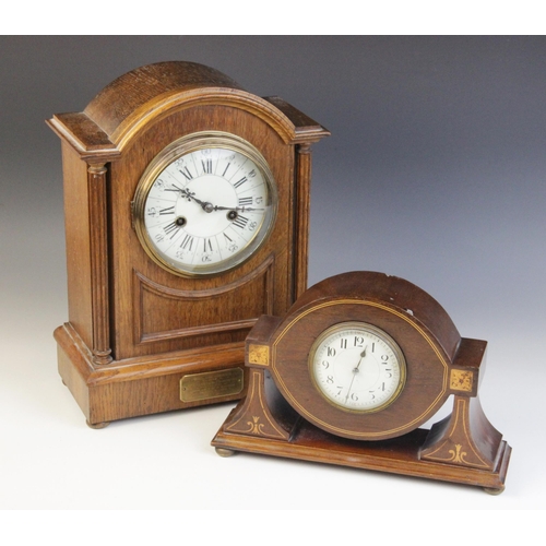 685 - An Edwardian oak cased mantel clock, the arched case enclosing a 13cm white enamelled dial applied w... 