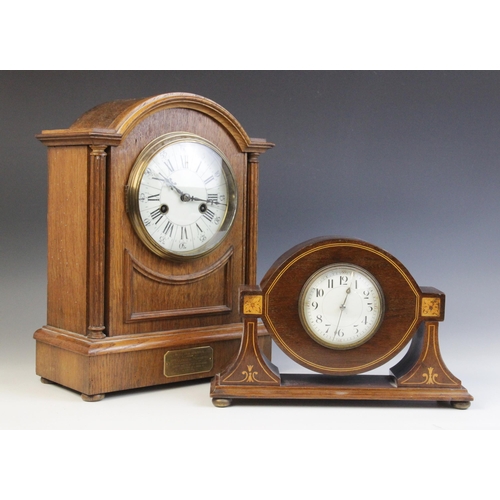 685 - An Edwardian oak cased mantel clock, the arched case enclosing a 13cm white enamelled dial applied w... 