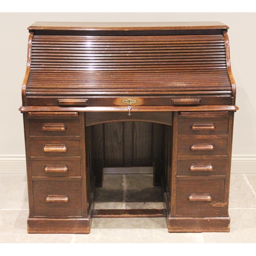 809 - An early 20th century oak roll top desk, the tambour front opening to an arrangement of small drawer... 