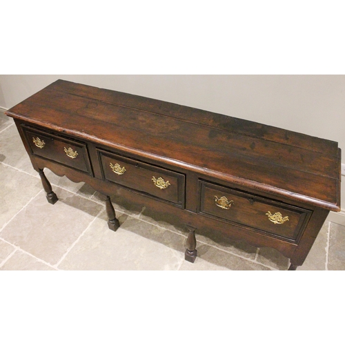 706 - An early 18th century oak dresser base, the three plank moulded top above three lip moulded frieze d... 