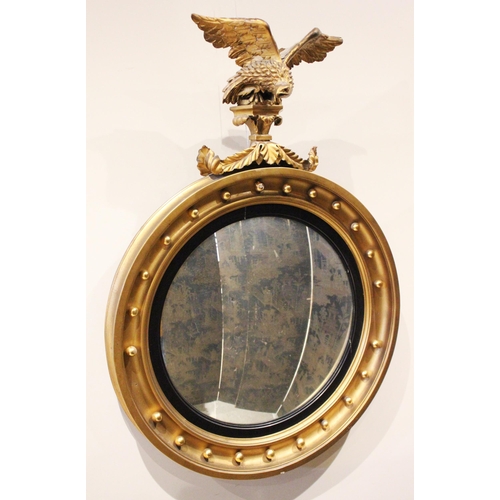 681 - A Regency style giltwood circular wall mirror, 19th century, the eagle crest above the convex mirror... 