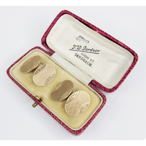 101A - A pair of George V 9ct gold cufflinks, each oval panel with engine turned detail and engraved floral... 