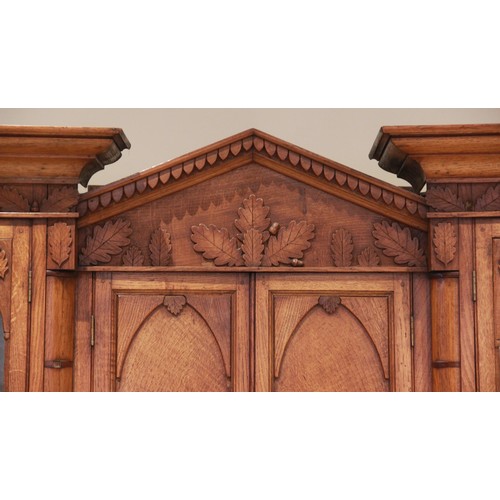 783 - A mid 19th century inverted breakfront oak housekeepers cupboard, the central architectural pediment... 