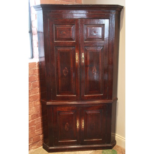 732 - A George III oak and mahogany cross banded freestanding corner cupboard, the moulded cornice above a... 