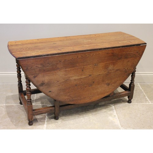 709A - An 18th/19th century oak drop leaf dining table, the oval top raised upon bobbin turned and block su... 