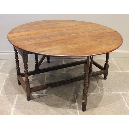 709A - An 18th/19th century oak drop leaf dining table, the oval top raised upon bobbin turned and block su... 