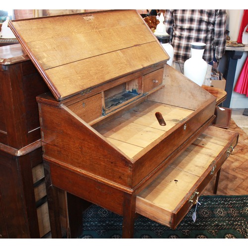 739 - A George III oak clerk’s desk, the hinged slope opening to two small drawers and a pigeon hole, abov... 