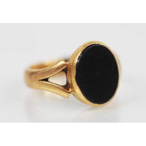 107 - A 22ct gold onyx set ring, the plain polished oval panel measuring 11mm x 9mm, bezel set to split sh... 