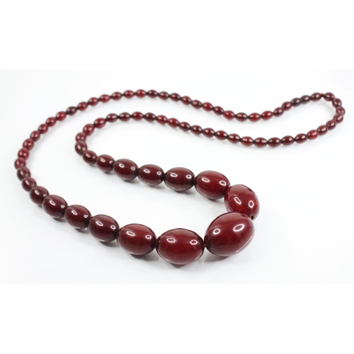 108 - An amber bead necklace, comprising seventy-three graduated polished oval cherry amber beads, measuri... 