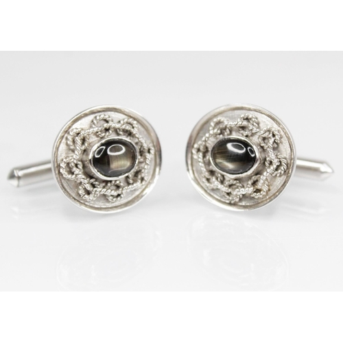 144 - A pair of 14ct white gold synthetic star sapphire cufflinks, each designed as a black star sapphire ... 