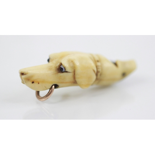 171 - A Victorian carved ivory dog whistle, modelled as a hound with glass eyes and gold coloured ring to ... 