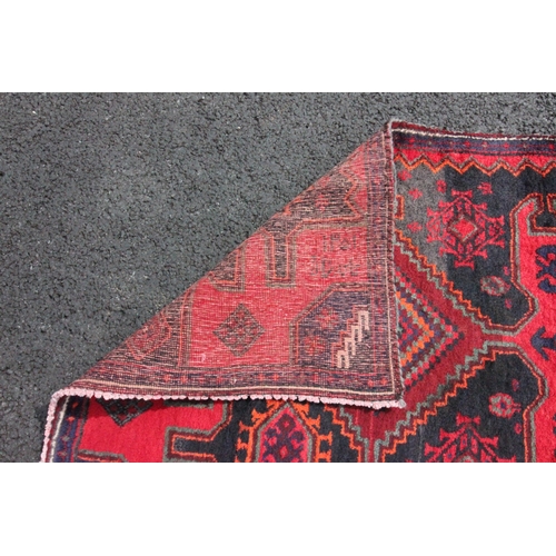 481 - An Iranian red ground floor runner, the central medallion set to a red panel extending to geometric ... 