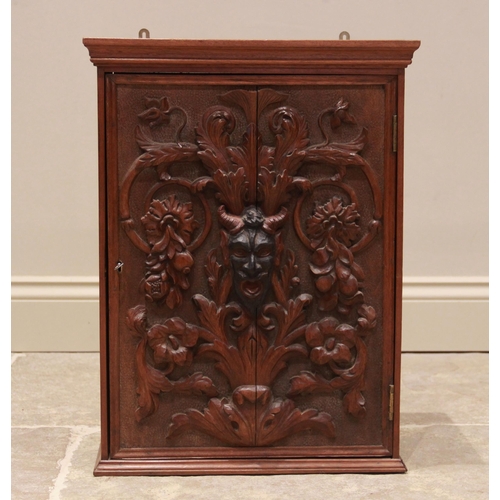 729 - A late 19th century carved walnut wall hanging cupboard, the single door centred with a carved kramp... 