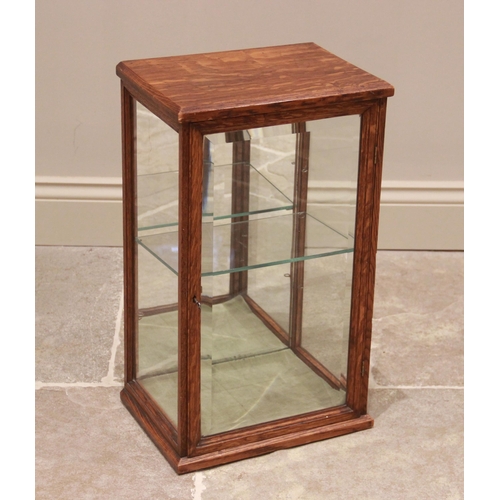 753 - An early 20th century oak counter top display cabinet, the bevelled glass single door opening to a m... 