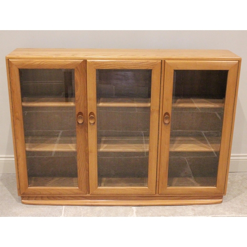 761 - An Ercol light elm floor standing glazed display cabinet, mid 20th century, with one single door and... 