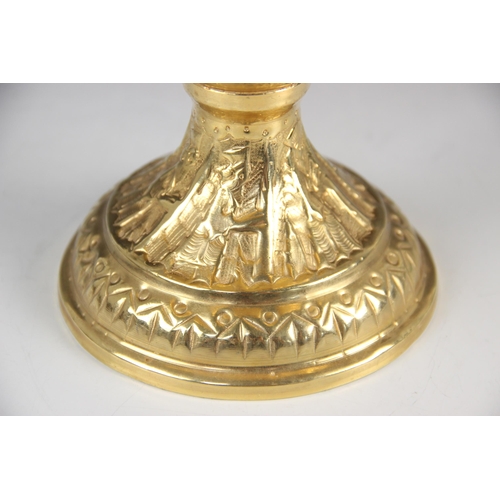 68 - A gold coloured pedestal dish, the circular bowl embossed with a continuous frieze of figures in pro... 