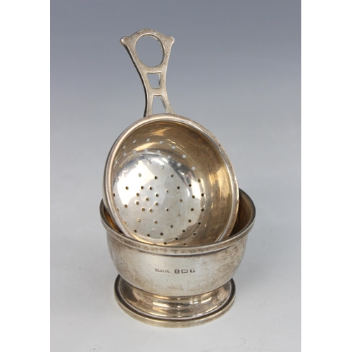 63 - A silver tea strainer and stand, G W Lewis & Co Birmingham 1943, with openwork handle, 3.5cm high, w... 