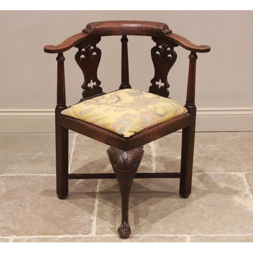 688 - A 19th century carved oak corner chair, the top rail with carved leaf detail and scroll terminals, u... 