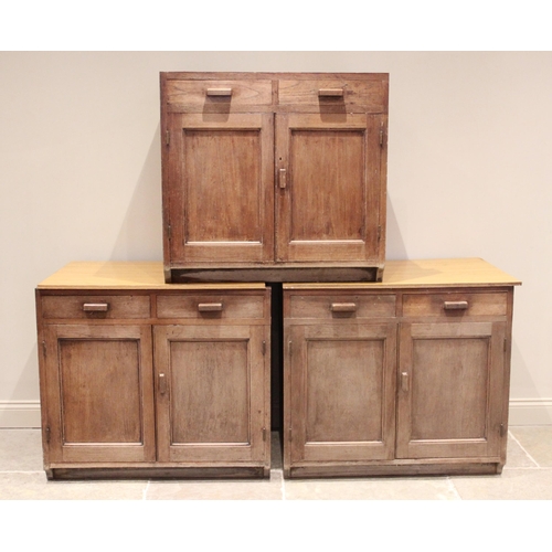 721 - A set of three early 20th century oak cupboards, each with two drawers above a pair of cupboard door... 