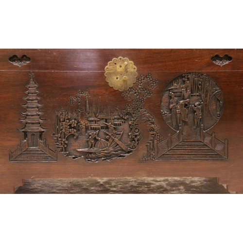 735 - A Chinese camphor wood chest, mid 20th century, the hinged cover carved in deep relief with pagoda l... 