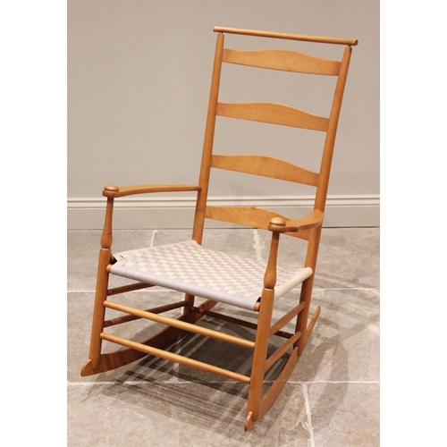 742 - A Shakers beech wood rocking chair, the ladder back above out swept arms and a woven seat, raised up... 