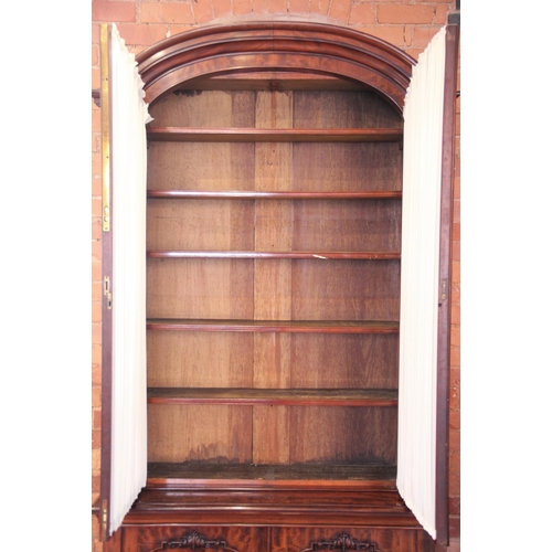 670 - A Victorian mahogany library bookcase, the arched moulded cornice above a pair of fabric lined glaze... 