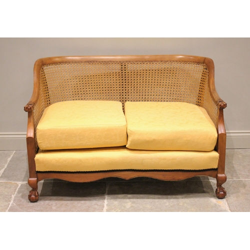 694 - A stained beech wood  bergère sofa, early 20th century, the curved back rail extending to egg and cl... 