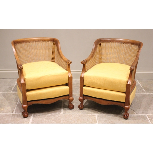 695 - A pair of stained beech wood bergère tub type chairs, early 20th century, the curved top rails exten... 