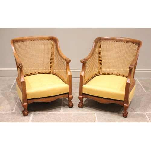 695 - A pair of stained beech wood bergère tub type chairs, early 20th century, the curved top rails exten... 