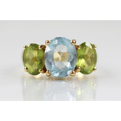 77 - A topaz and peridot cocktail ring, the central oval blue topaz measuring 10mm x 8mm, with an oval pe... 