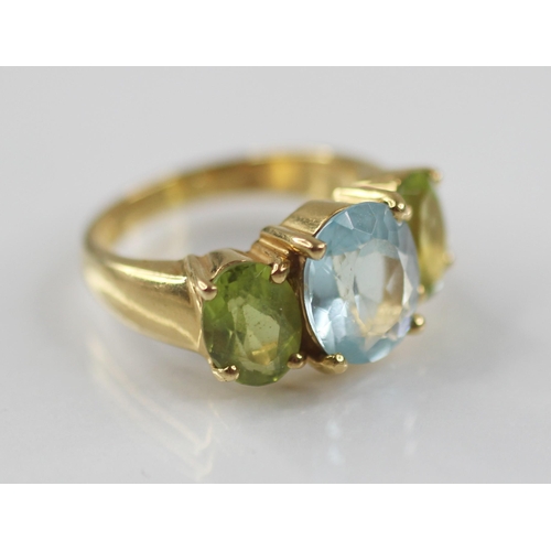 77 - A topaz and peridot cocktail ring, the central oval blue topaz measuring 10mm x 8mm, with an oval pe... 