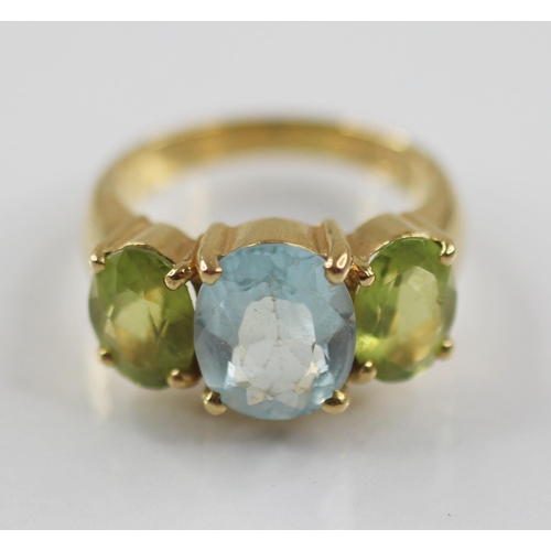 77 - A topaz and peridot cocktail ring, the central oval blue topaz measuring 10mm x 8mm, with an oval pe... 