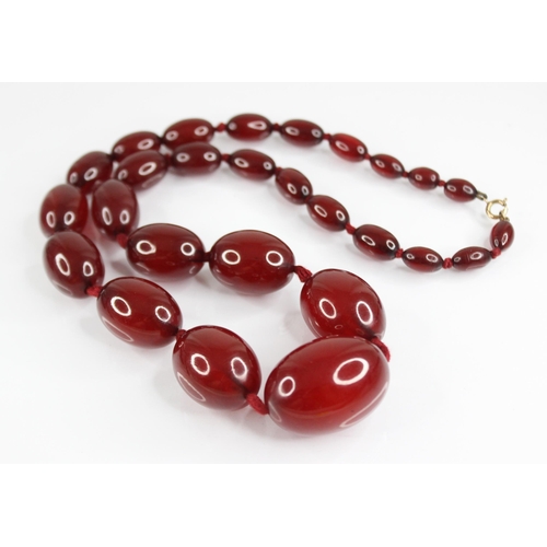 81 - A cherry amber bead necklace, comprising twenty-seven polished oval amber beads, measuring between 1... 