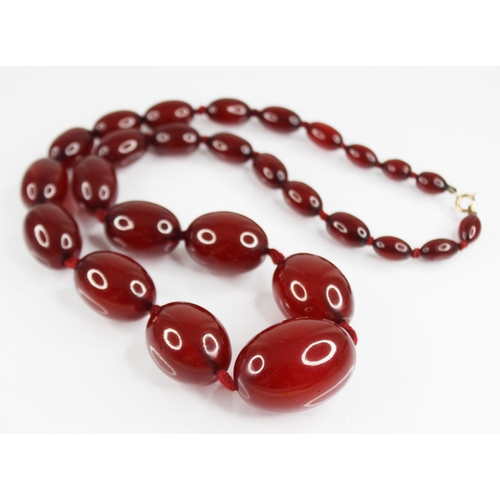 81 - A cherry amber bead necklace, comprising twenty-seven polished oval amber beads, measuring between 1... 