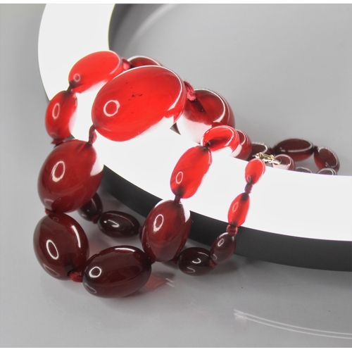 81 - A cherry amber bead necklace, comprising twenty-seven polished oval amber beads, measuring between 1... 