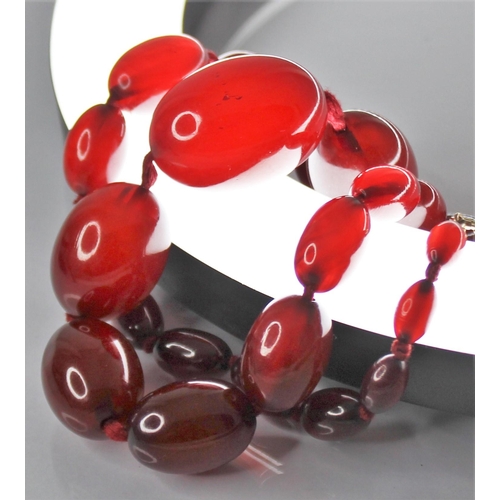 81 - A cherry amber bead necklace, comprising twenty-seven polished oval amber beads, measuring between 1... 