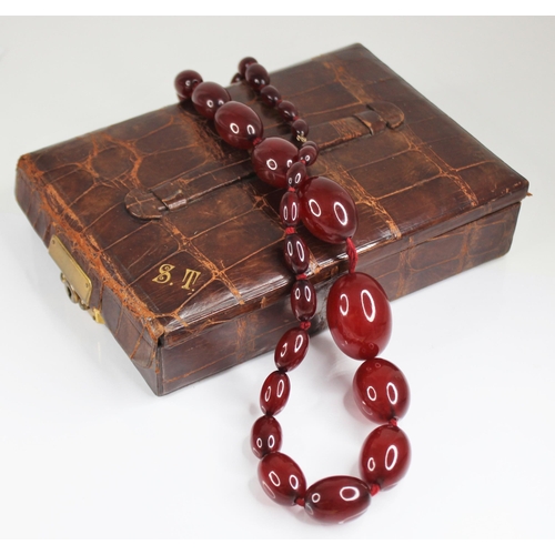 81 - A cherry amber bead necklace, comprising twenty-seven polished oval amber beads, measuring between 1... 