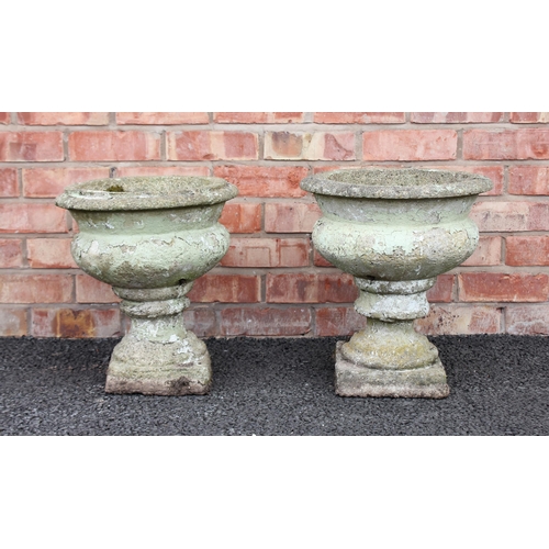 743 - A pair of reconstituted stone garden urns, of lobed bowl form raised upon an integrated plinth base,... 