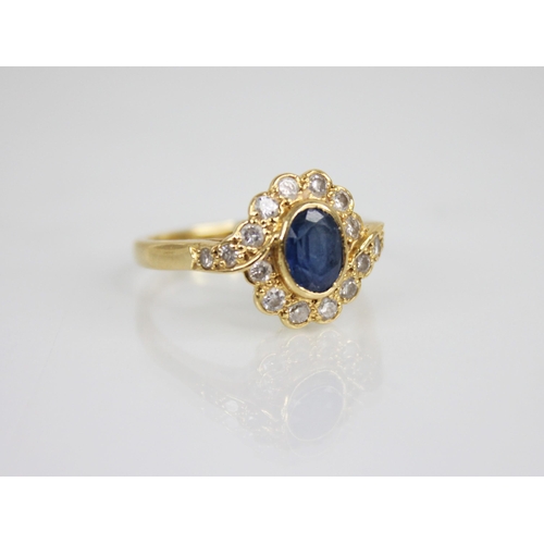 118 - A sapphire and diamond 18ct gold cluster ring, the central oval mixed cut sapphire measuring 6.5mm x... 