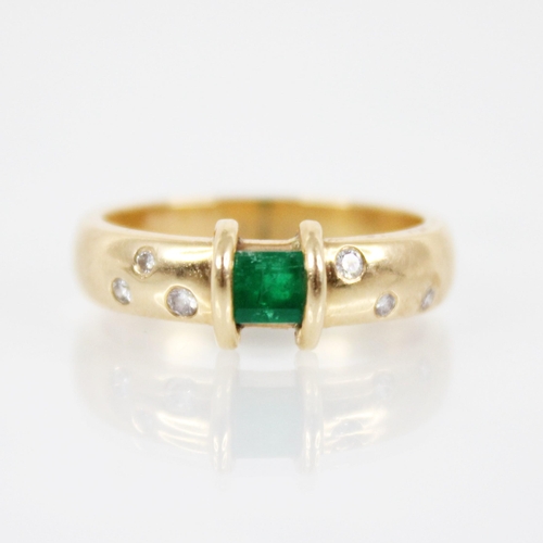 124 - An emerald and diamond ring, the central rectangular step cut emerald measuring 3.8mm x 4.8mm, to an... 