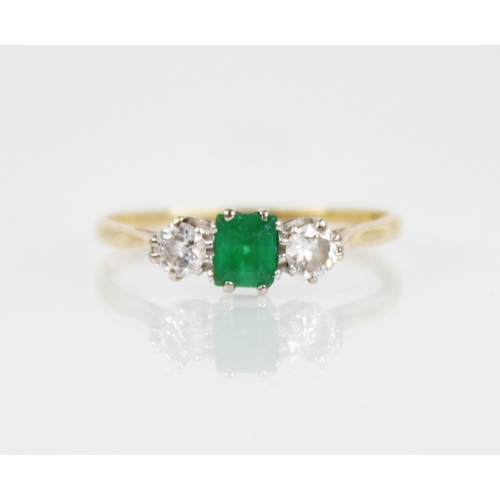 125 - An emerald and diamond three stone ring, the central rectangular step cut emerald measuring 4.5mm x ... 